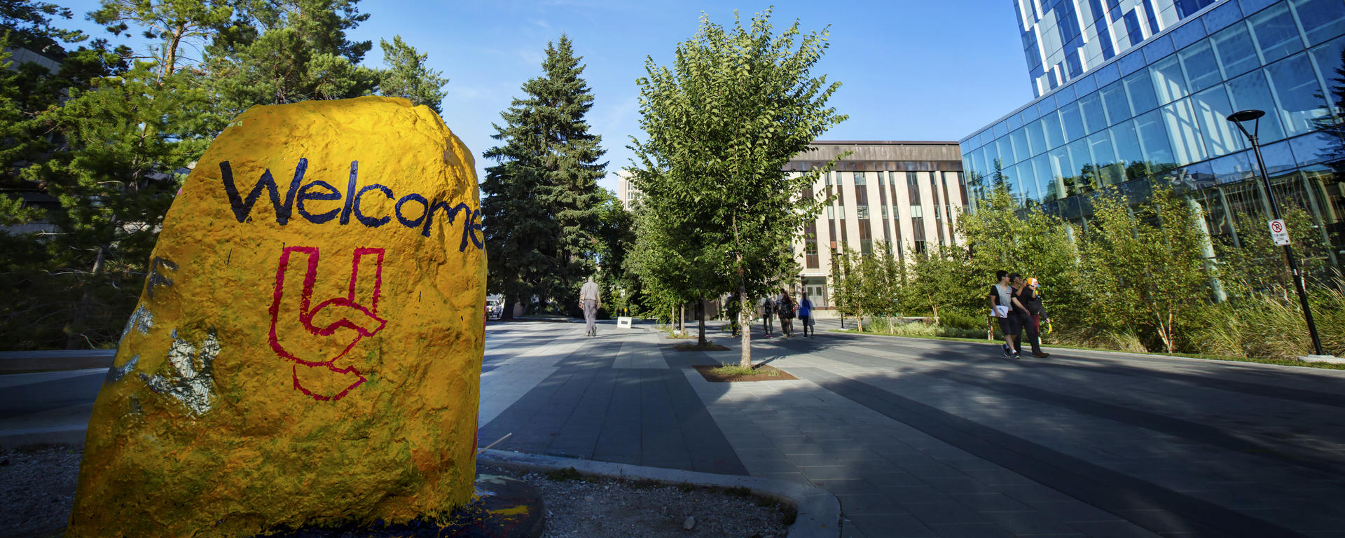 A large rock is painted yellow and says "Welcome"