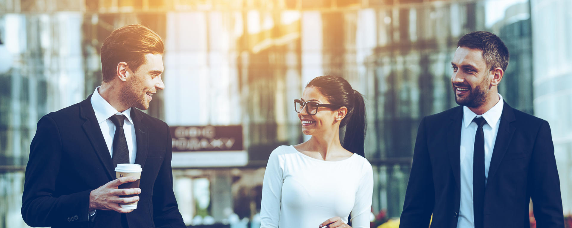 Three people in business attire walking downtown and talking