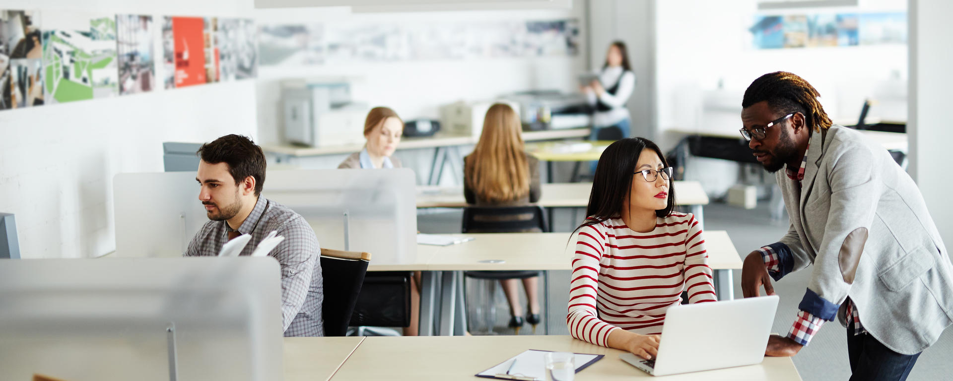 Several people work in a brightly-lit open concept office space. 