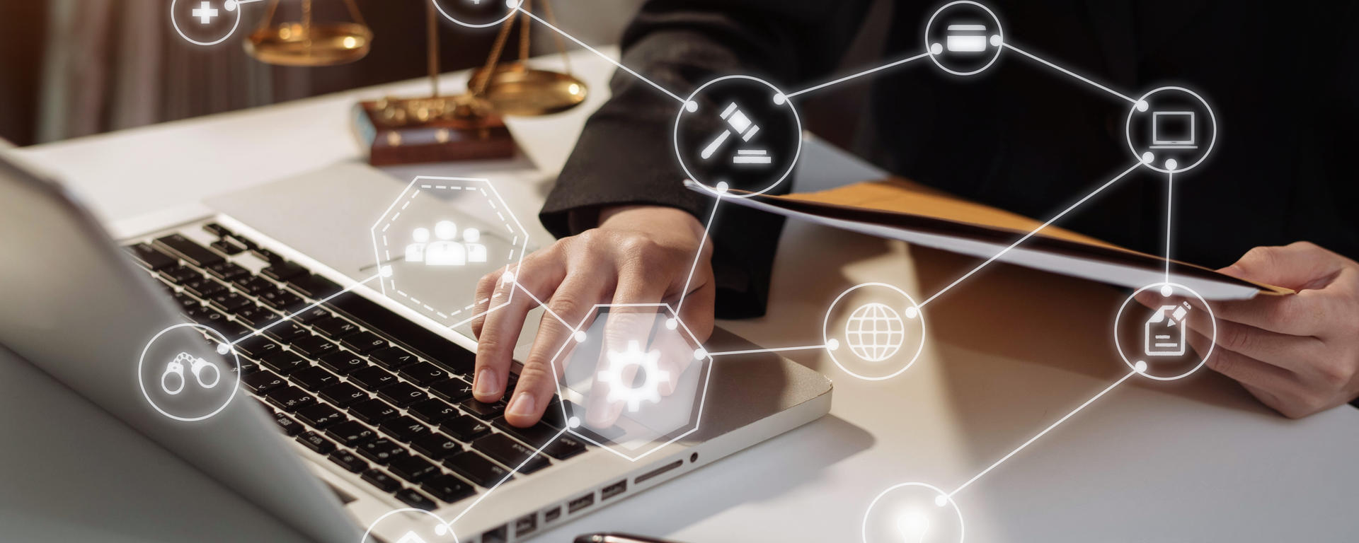 A person works on a laptop and holds a file in one hand. The scales of justice are in the background and a gavel is in the foreground. Graphics for money, law, the world, people, ideas are overlaid over top of the image. 