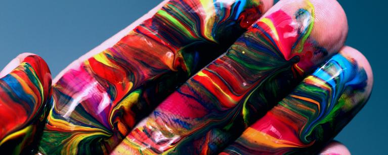 A hand swirled with many different colours of paint