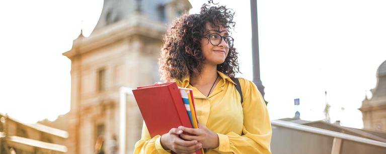 Woman in yellow jacket holding books 