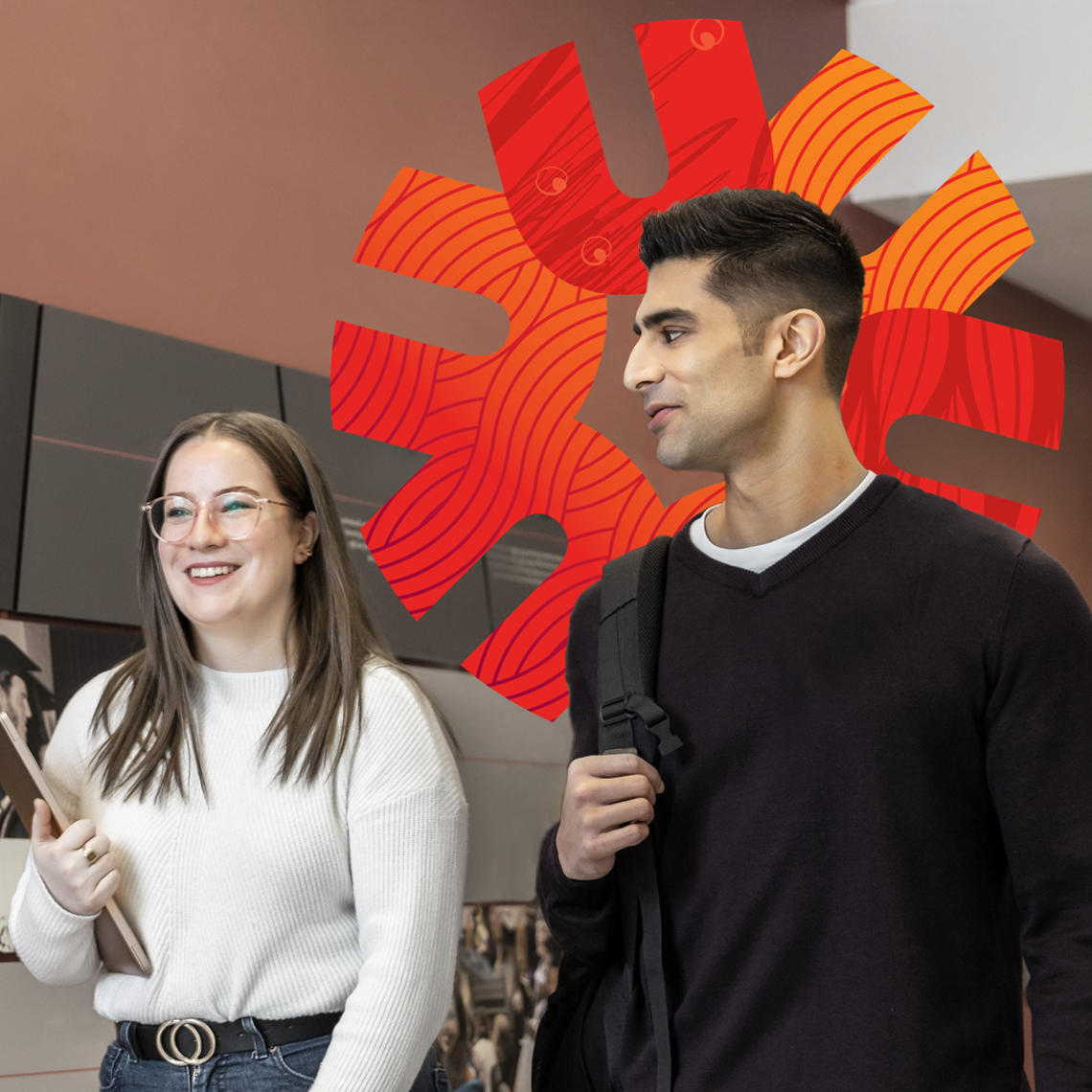 Two students walk past a display on a wall in the law school.