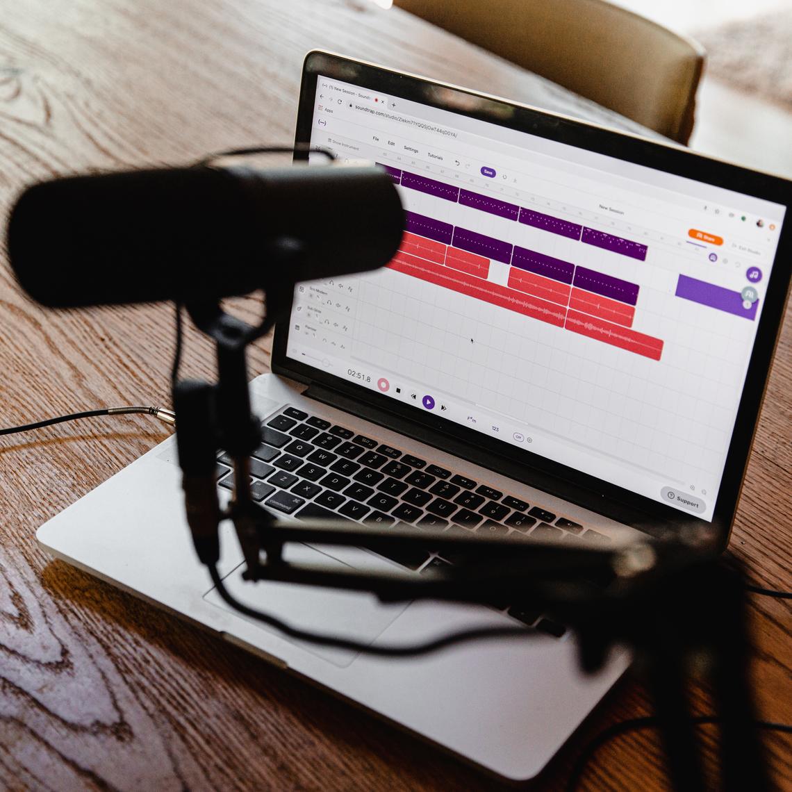 A podcasting microphone and laptop sit on a table