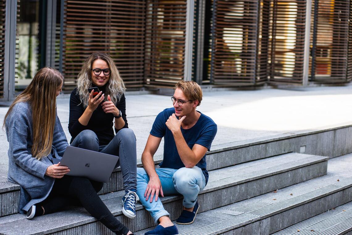 Campus in Leiden in Netherlands. Three persons sitting on the stairs and talking to each other