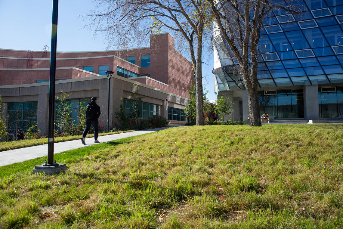 A student walks between Murray Fraser Hall and McKimmie Tower