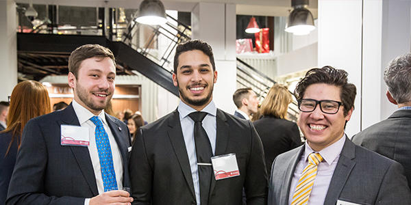 Three students smile during a networking reception