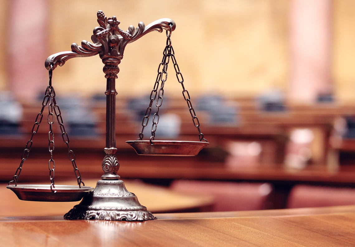 The scales of justice stand on a table in a courtroom.