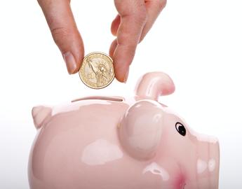 Hand dropping a coin into a piggy bank