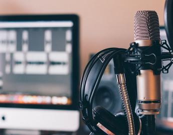 Podcast setup with a microphone, headphones, and computer