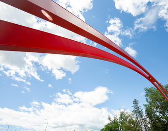The iconic red arch sits below a partly-cloudy blue sky